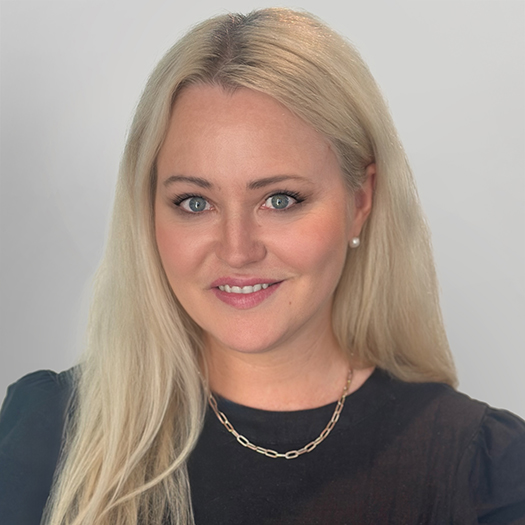 Professional headshot of Kate White, Legal Advisor and Special Counsel at Madison Marcus Law Firm, specialising in global mobility, immigration, migration, and visa law for Australia. She has long blonde hair, blue eyes, and is wearing a black top and gold chain necklace against a light grey background.
